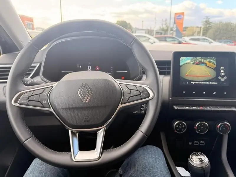 Vue intérieure centrée sur le volant de la Renault Clio V noire, avec tableau de bord numérique et écran multimédia affichant la caméra de recul.