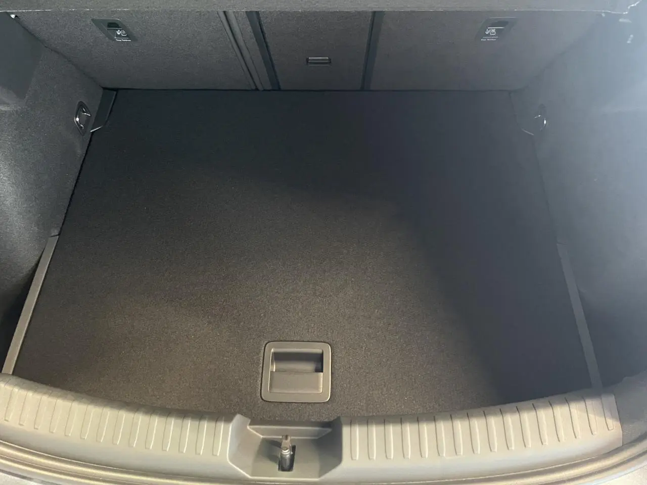 Coffre ouvert vu de dessus d'une CUPRA Leon gris, montrant un espace de chargement propre et vide.
