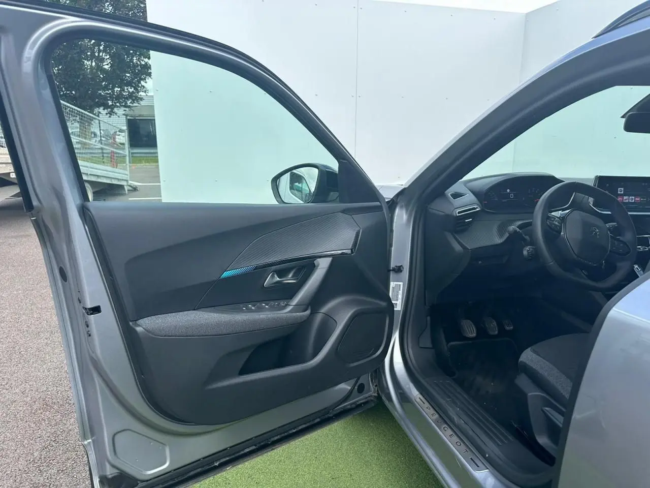 Intérieur avant gauche du Peugeot 2008 gris clair 2022, montrant porte ouverte et tableau de bord moderne.