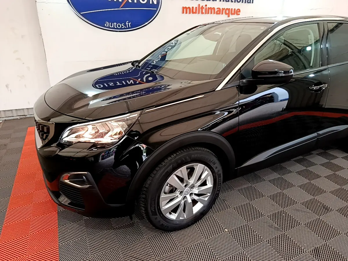 Vue 3/4 avant droit d'un Peugeot 3008 noir brillant avec phares allumés et jantes argentées sur sol carrelé.