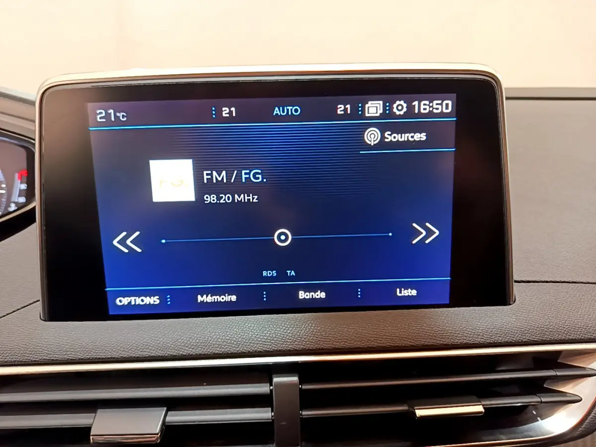 Écran tactile central affichant la radio FM dans l'habitacle du Peugeot 3008 noir, vue rapprochée du tableau de bord.