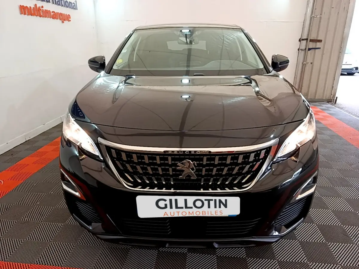 Vue frontale d'un Peugeot 3008 noir 2019 avec calandre chromée et phares allumés en intérieur showroom.