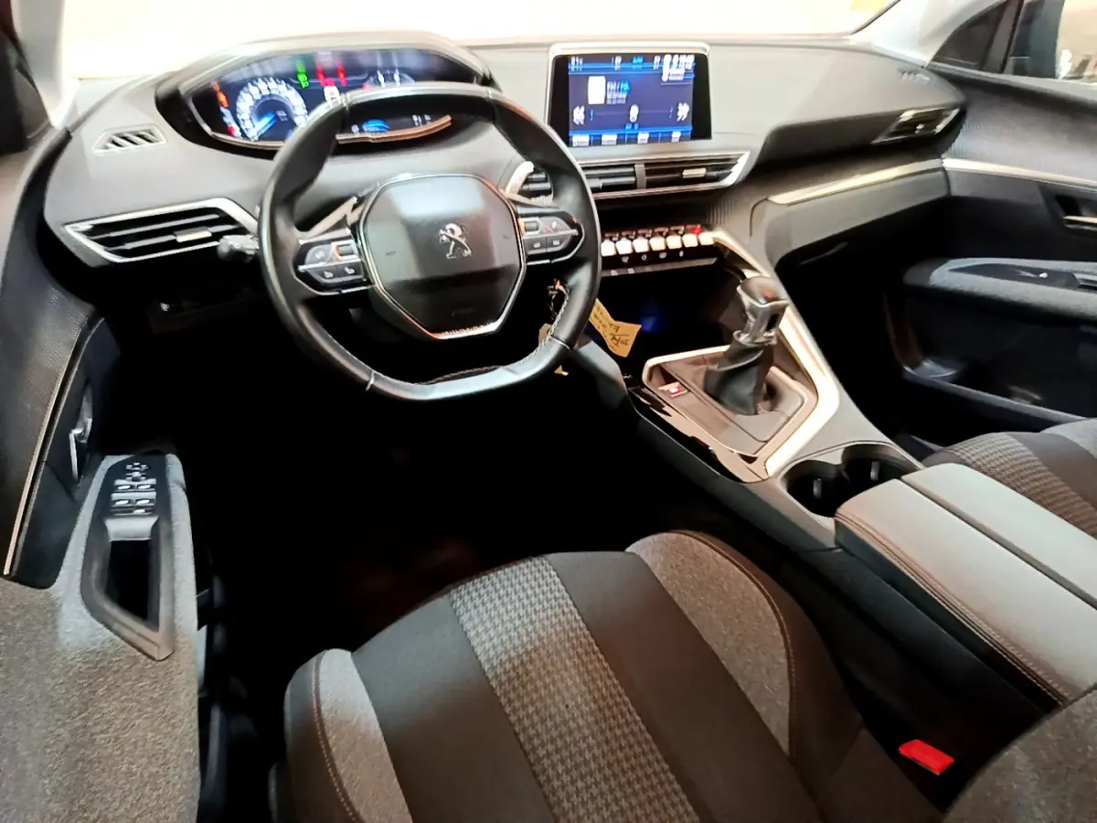 Vue intérieure du poste de conduite du Peugeot 3008 noir, avec volant compact, écran tactile central et levier de vitesses manuel.