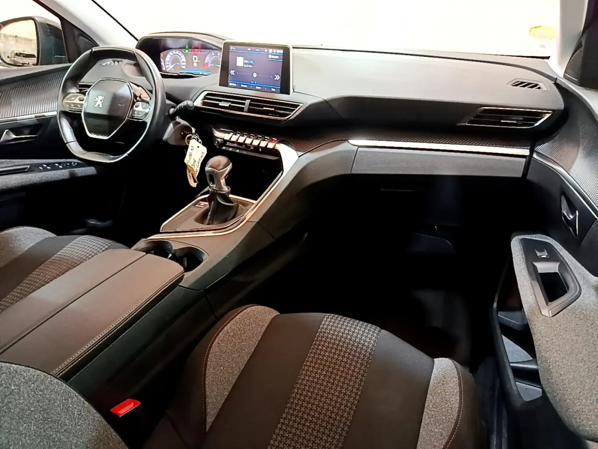 Intérieur du Peugeot 3008 2019, vue côté conducteur, tableau de bord noir avec écran tactile et volant cuir compact.