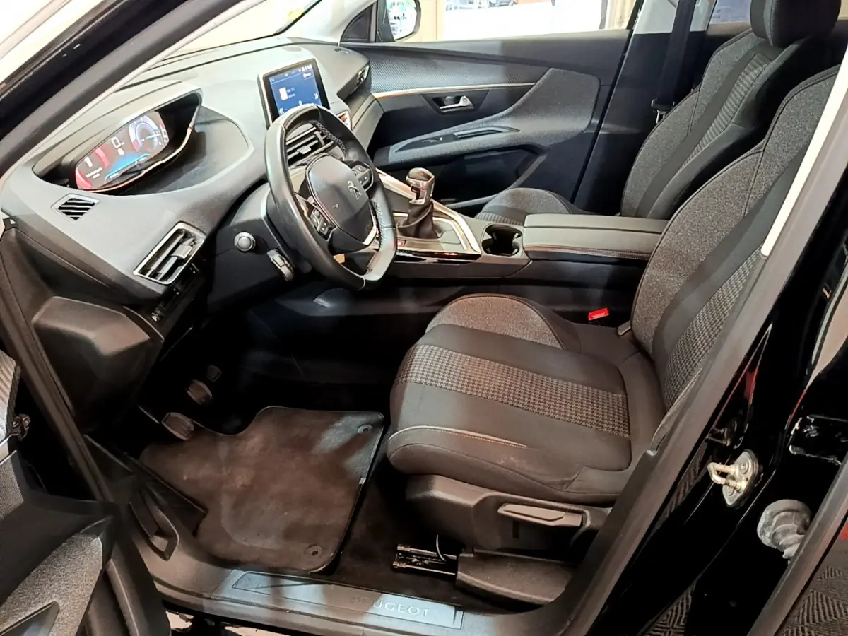 Intérieur avant droit du Peugeot 3008 noir 2019, volant cuir, tableau de bord numérique et sièges tissu gris.