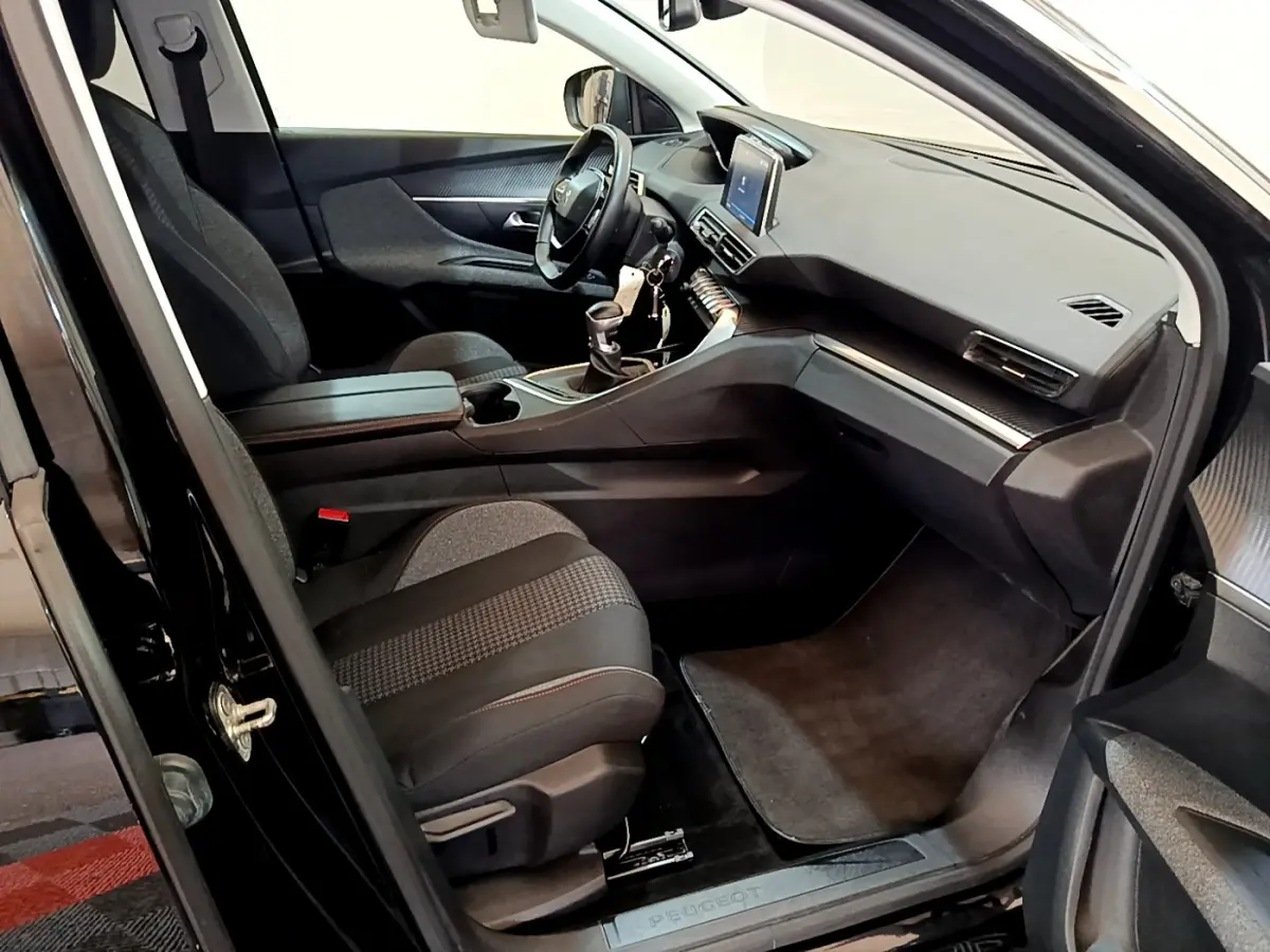 Intérieur avant droit du Peugeot 3008 noir 2019, montrant sièges tissu, tableau de bord avec écran tactile et volant cuir.