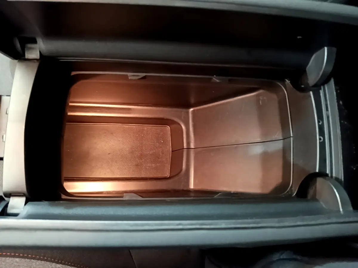 Gros plan sur le rangement central intérieur du Peugeot 3008 noir, montrant un espace vide et propre sous l'accoudoir.