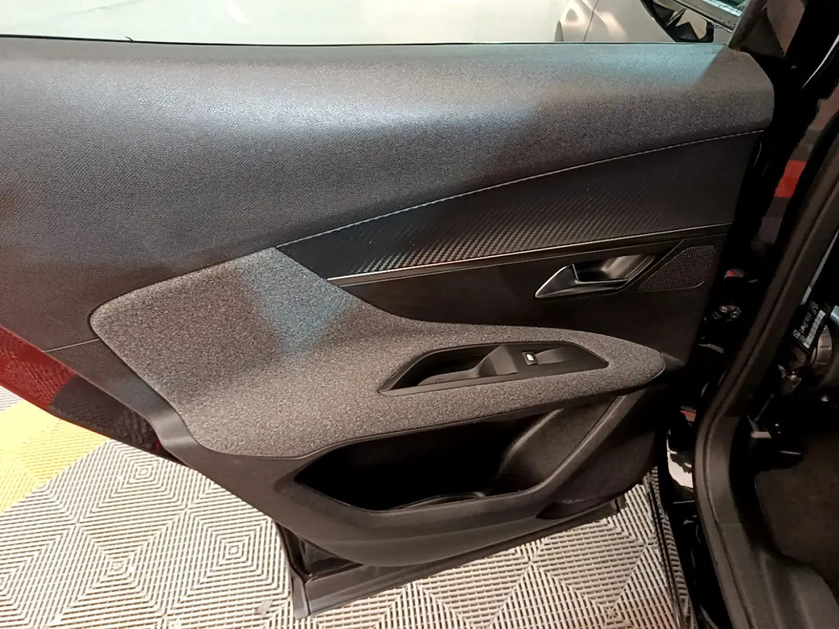 Gros plan sur la porte côté gauche du Peugeot 3008 noir, mettant en valeur les matériaux texturés et la poignée intérieure.