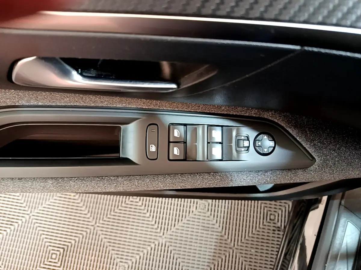 Gros plan sur la commande des vitres et rétroviseurs côté conducteur du Peugeot 3008 noir, intérieur tissu gris.