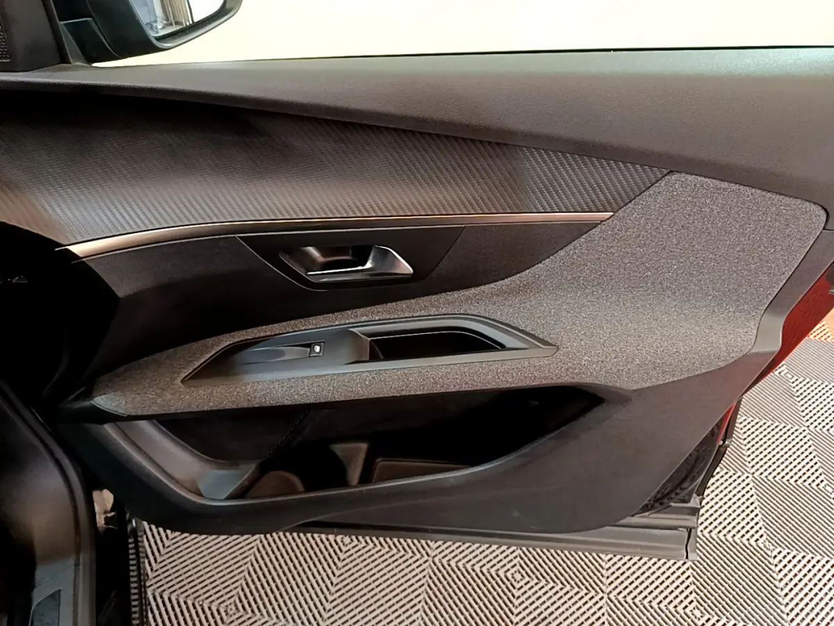 Gros plan sur la porte côté gauche du Peugeot 3008 noir, mettant en valeur la texture grise et la poignée intérieure métallique.