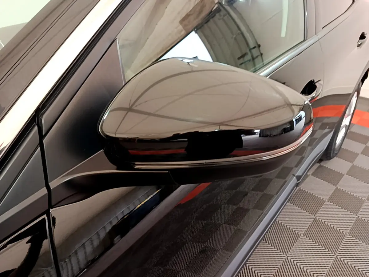 Rétroviseur côté gauche noir brillant du Peugeot 3008 2019, avec reflet de l'environnement intérieur.