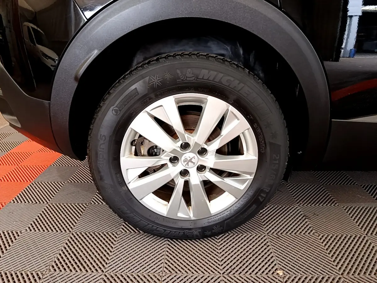 Gros plan sur la roue avant droite d'un Peugeot 3008 noir, avec jante alliage et pneu Michelin hiver.