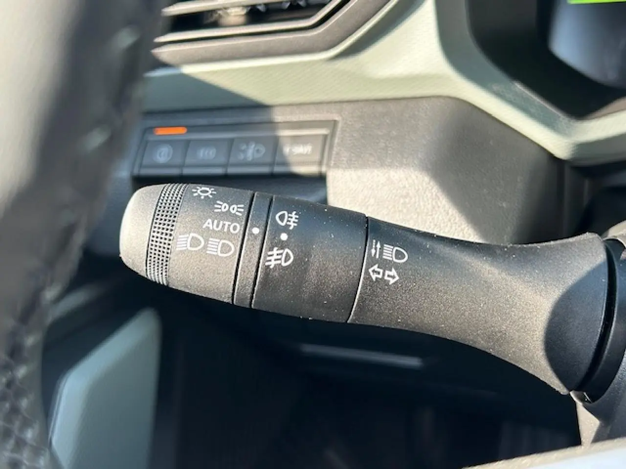 Gros plan sur la commande des phares et clignotants du Dacia Duster III 1.6 Hybrid 140, intérieur noir.