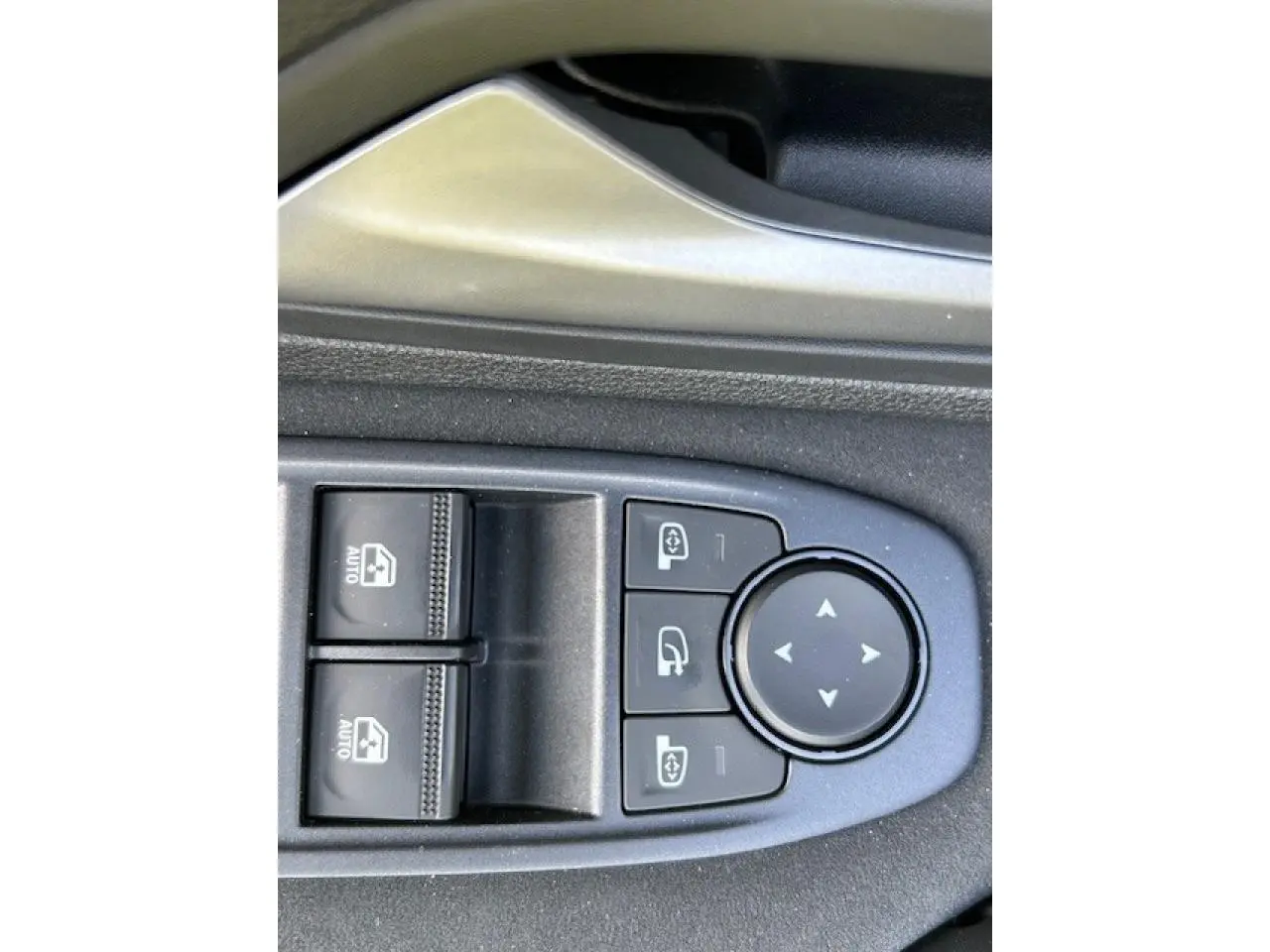 Gros plan sur les commandes électriques de réglage des rétroviseurs et lève-vitres côté conducteur du Dacia Duster kaki Dusty 2025.