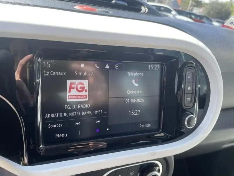 Tableau de bord de Renault Twingo III bleu dragée, affichage multimédia avec radio FG et options téléphone visibles.