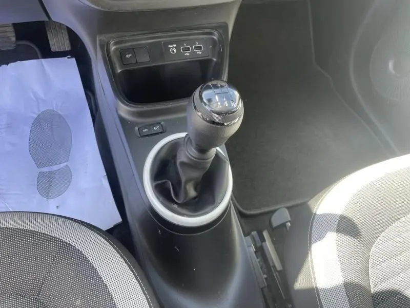 Gros plan sur le levier de vitesses manuel de la Renault Twingo III 2022, avec console noire et sièges gris à motifs.