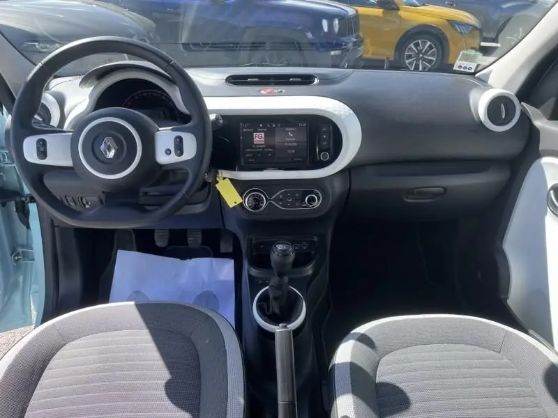 Vue intérieure avant de la Renault Twingo III bleu dragée 2022, avec tableau de bord moderne et boîte manuelle visible.