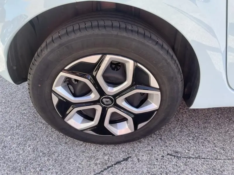 Gros plan sur la roue avant droite de la Renault Twingo III bleu dragée avec jante noire et argentée au design hexagonal.