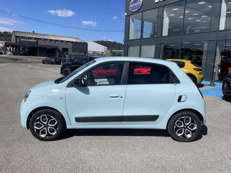 Profil droit d'une Renault Twingo III bleu dragée 2022, avec baguettes latérales noires et jantes à motifs géométriques.