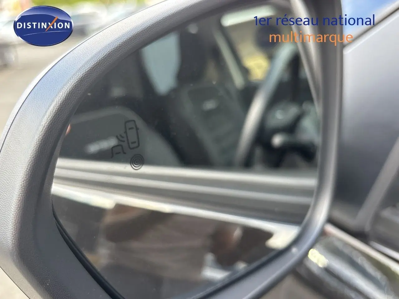 Gros plan sur le rétroviseur extérieur gauche du Dacia Duster noir 2024, avec affichage d'alerte d'angle mort visible.