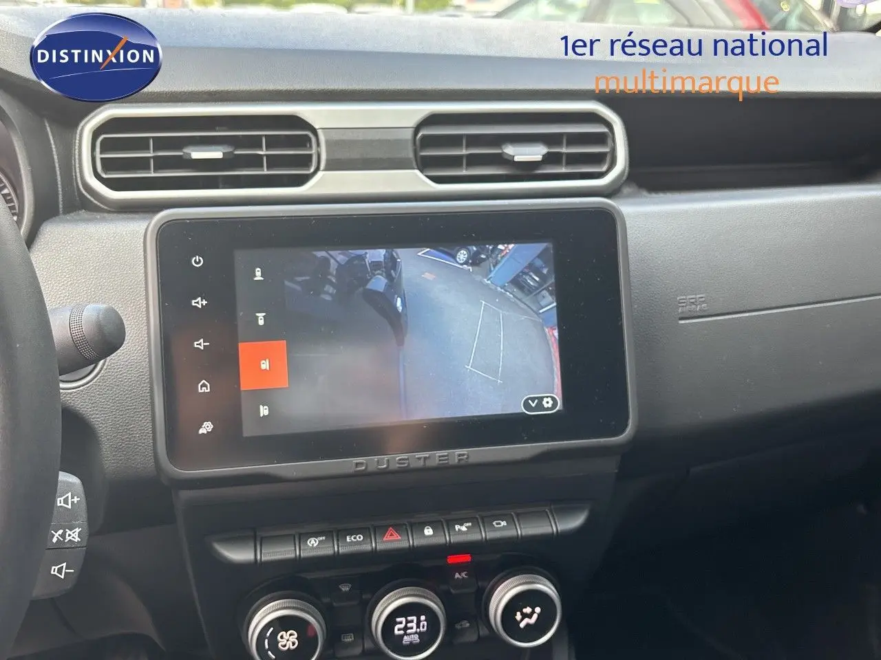 Intérieur du Dacia Duster 2024 noir, vue sur l’écran central tactile affichant la caméra de recul et la console de climatisation.
