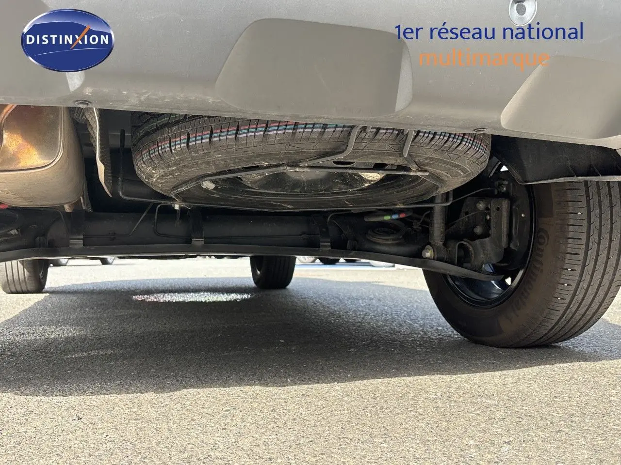 Vue en contre-plongée sous le Dacia Duster noir 2024, montrant la roue de secours et le train arrière.