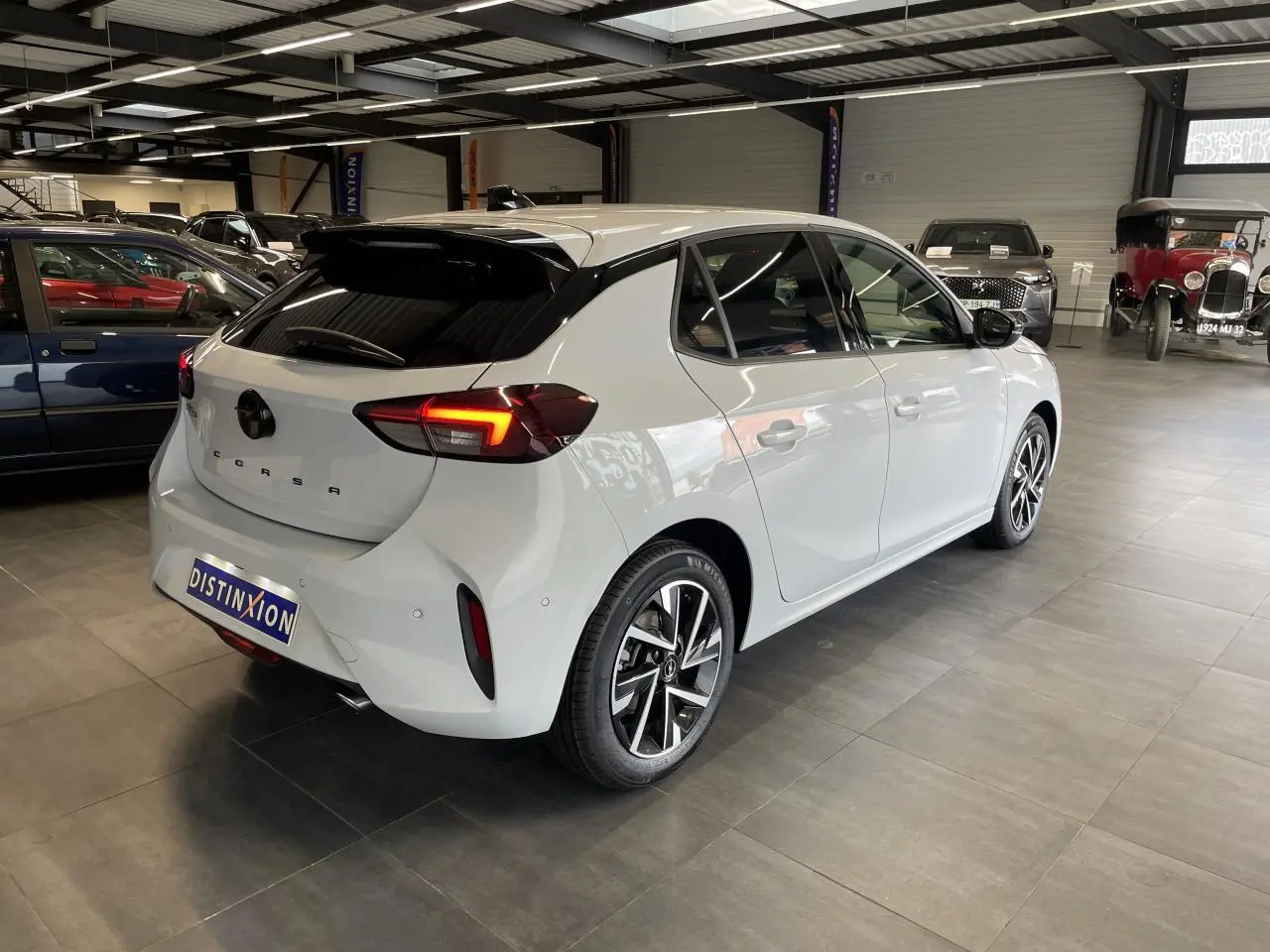 Opel Corsa blanche vue 3/4 arrière droit en intérieur avec feux arrière LED et jantes alliage diamantées.
