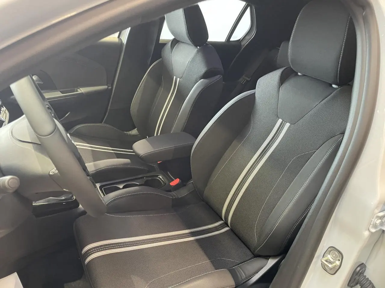 Vue intérieure côté conducteur de l'Opel Corsa 2026 blanche, sièges sport noirs avec bandes blanches centrales.