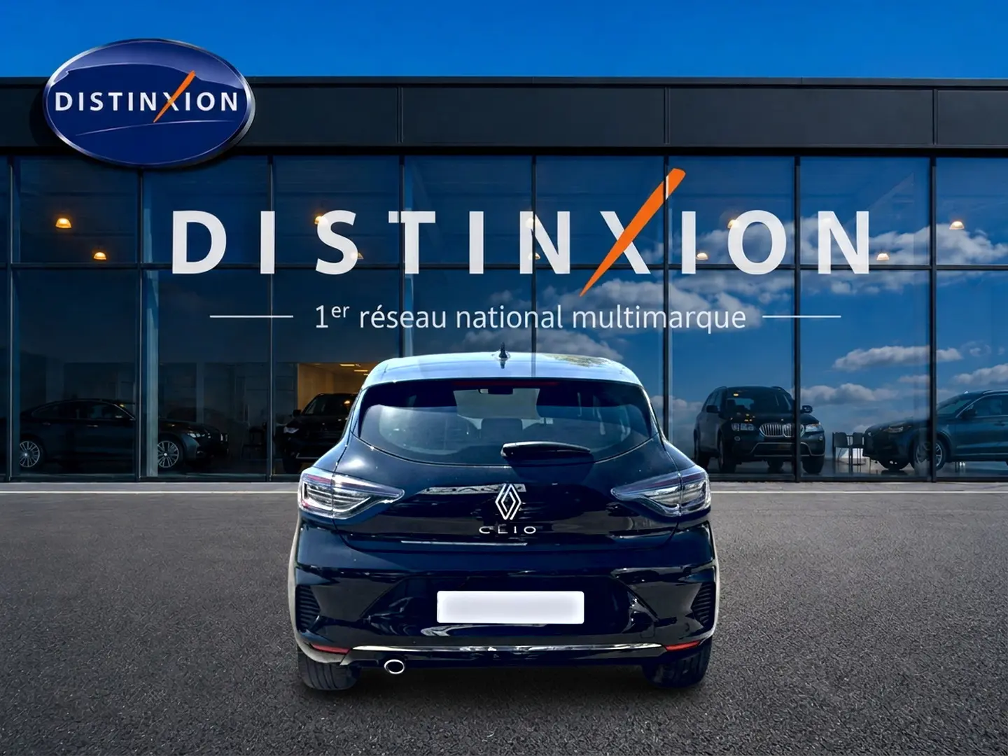 Vue arrière d'une Renault Clio V noire 2025, avec feux LED et sortie d'échappement chromée visible, devant un showroom Distinxion.