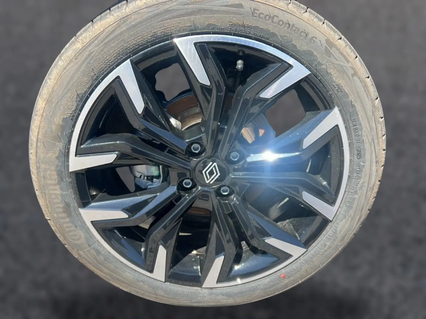 Gros plan sur une jante alliage noire et argentée avec logo Renault au centre, pneu Continental EcoContact 6 visible.