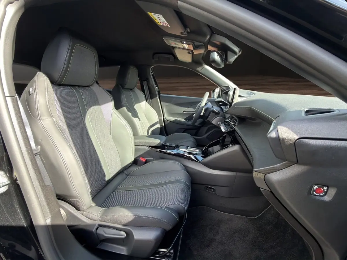 Intérieur avant droit du Peugeot 2008 Hybrid 145 e-DCS6 GT noir, sièges cuir noirs avec surpiqûres contrastées.