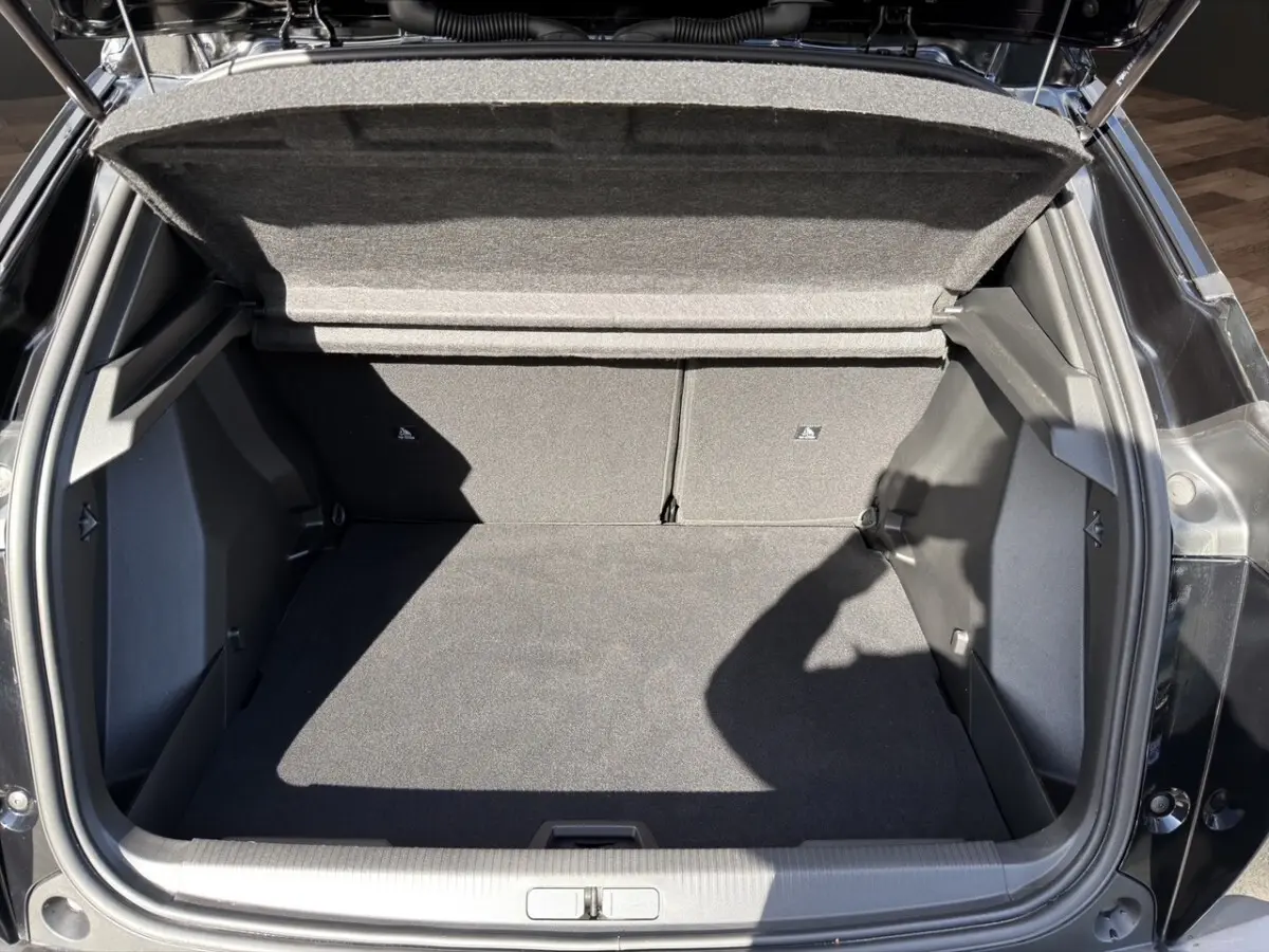 Coffre ouvert vu de dessus d’un Peugeot 2008 Hybrid 145 e-DCS6 GT noir, espace de rangement vide et propre.