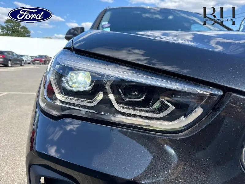 Gros plan sur le phare avant gauche du BMW X1 xDrive25eA 2021 en Saphirschwarz, mettant en valeur ses LED distinctives.