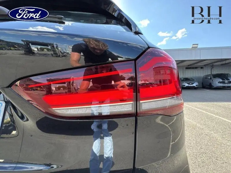 Gros plan sur le feu arrière droit rouge et blanc d'un BMW X1 xDrive25eA Saphirschwarz 2021, reflet sur la carrosserie noire.