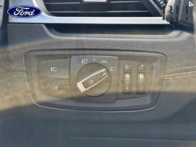 Gros plan sur le panneau de commande des phares d'un BMW X1 xDrive25eA 220ch xLine 2021 en Saphirschwarz.