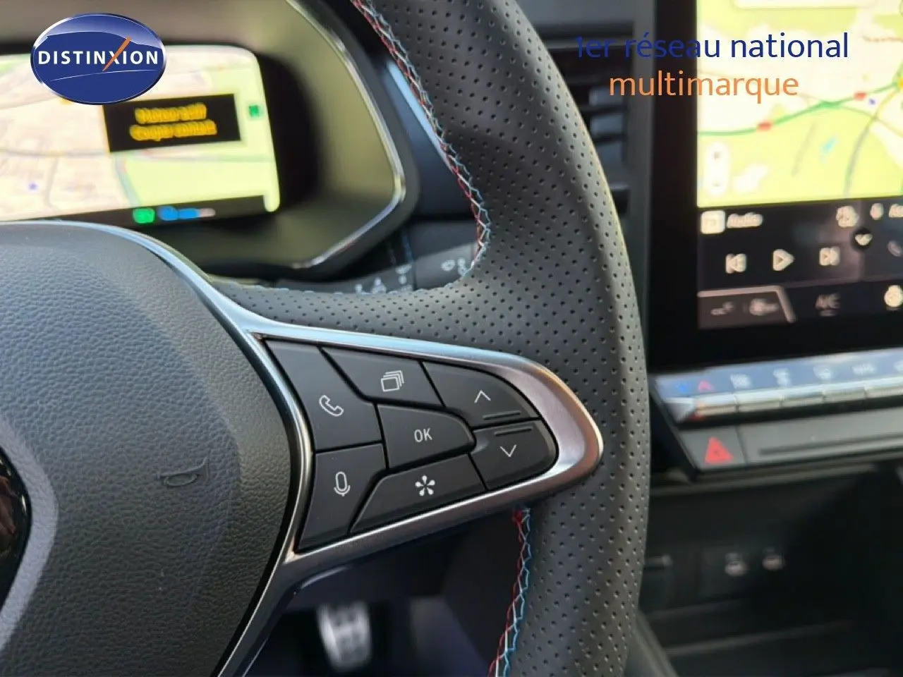 Gros plan sur le volant perforé avec commandes intégrées et tableau de bord numérique du Renault Captur blanc nacré 2025.