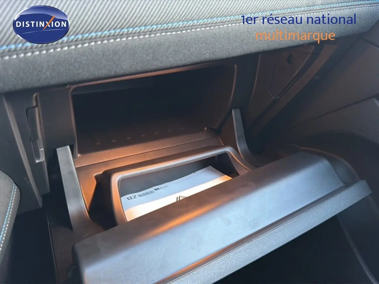 Gros plan sur la boîte à gants ouverte du Renault Captur 2025, intérieur noir avec surpiqûres bleues visibles.