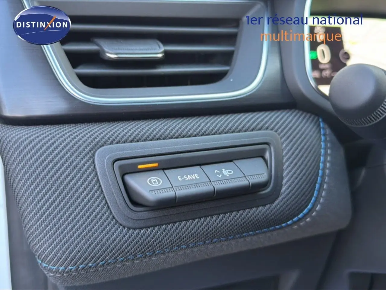 Détail intérieur du tableau de bord du Renault Captur blanc nacré, montrant les boutons de commande sur revêtement texturé gris.