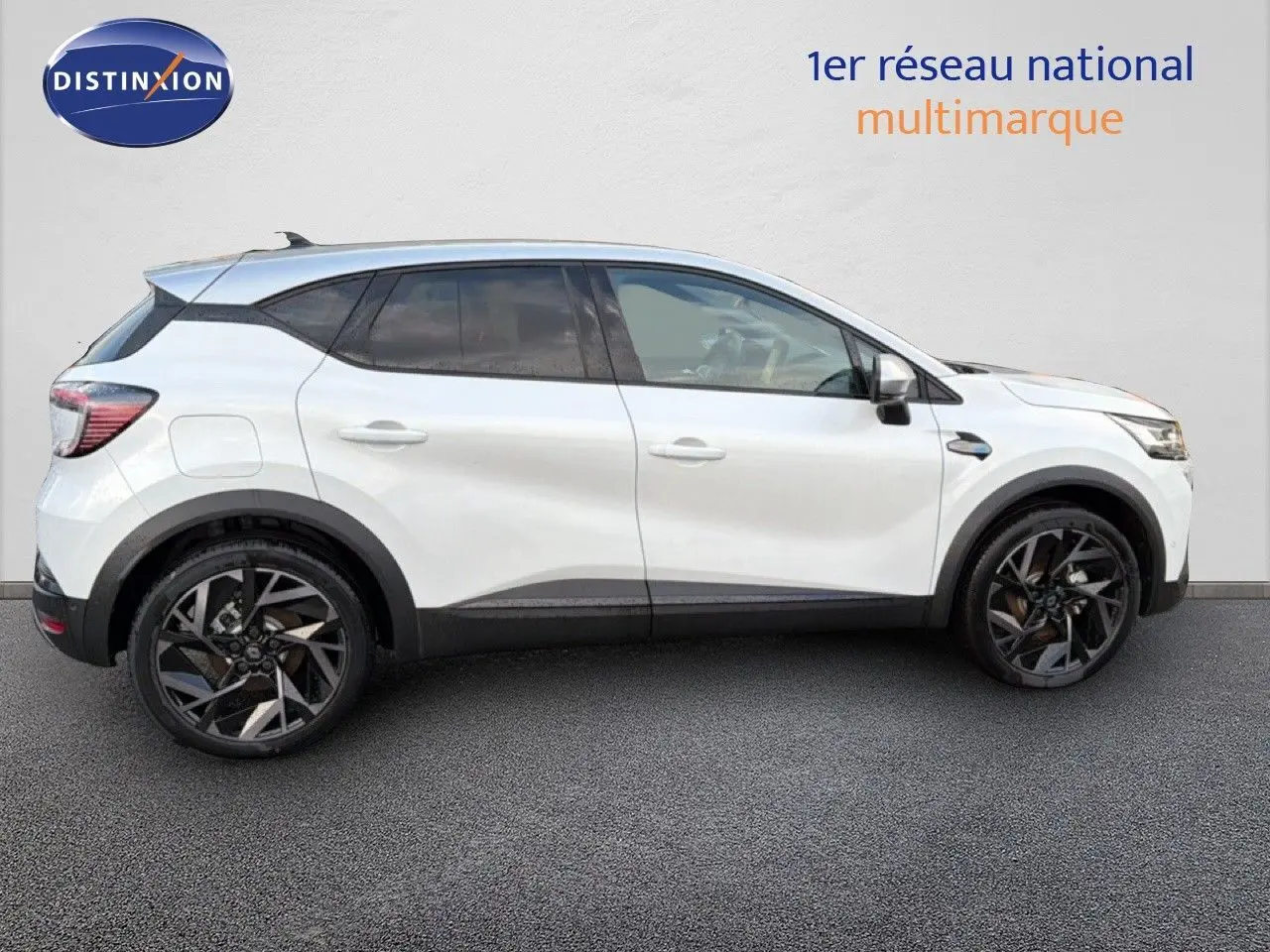 Profil côté gauche du Renault Captur blanc nacré avec toit gris, roues noires et jantes stylisées, sur fond neutre.