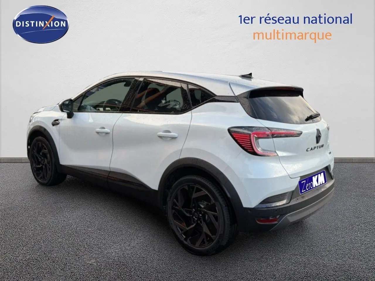 Vue 3/4 arrière droite du Renault Captur blanc nacré avec toit gris et jantes noires distinctives.