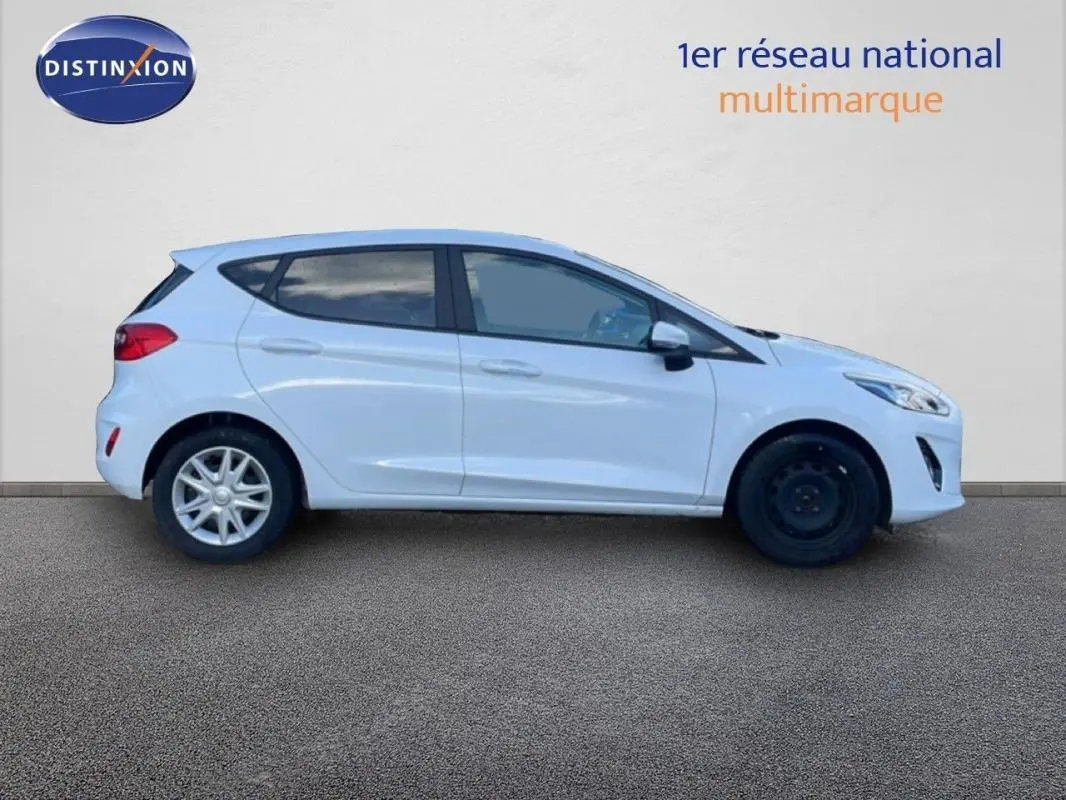 Profil droit d'une Ford Fiesta blanche 2020 avec vitres surteintées et jantes classiques, roue avant en acier noir.