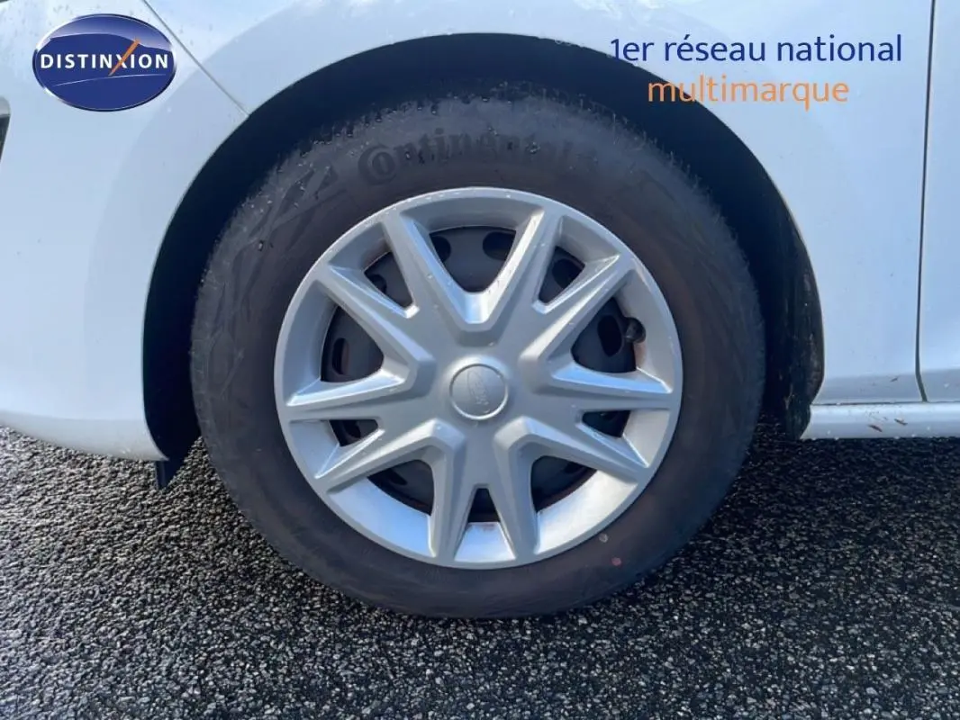 Gros plan sur la roue avant droite avec jante classique 15 pouces d'une Ford Fiesta blanche 2020.