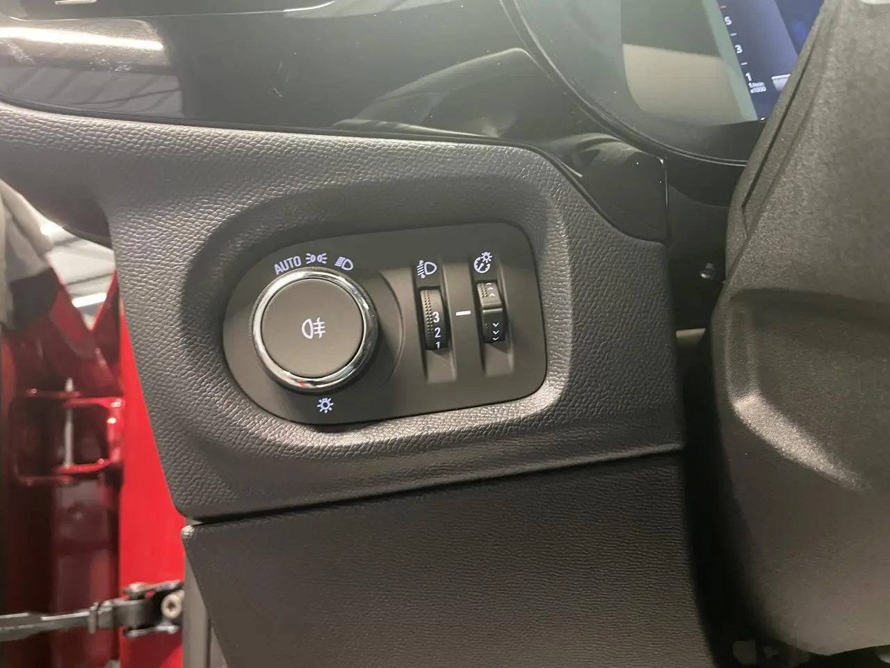 Détail du panneau de commandes d'éclairage à gauche du volant dans une Opel Corsa rouge, version 2026.