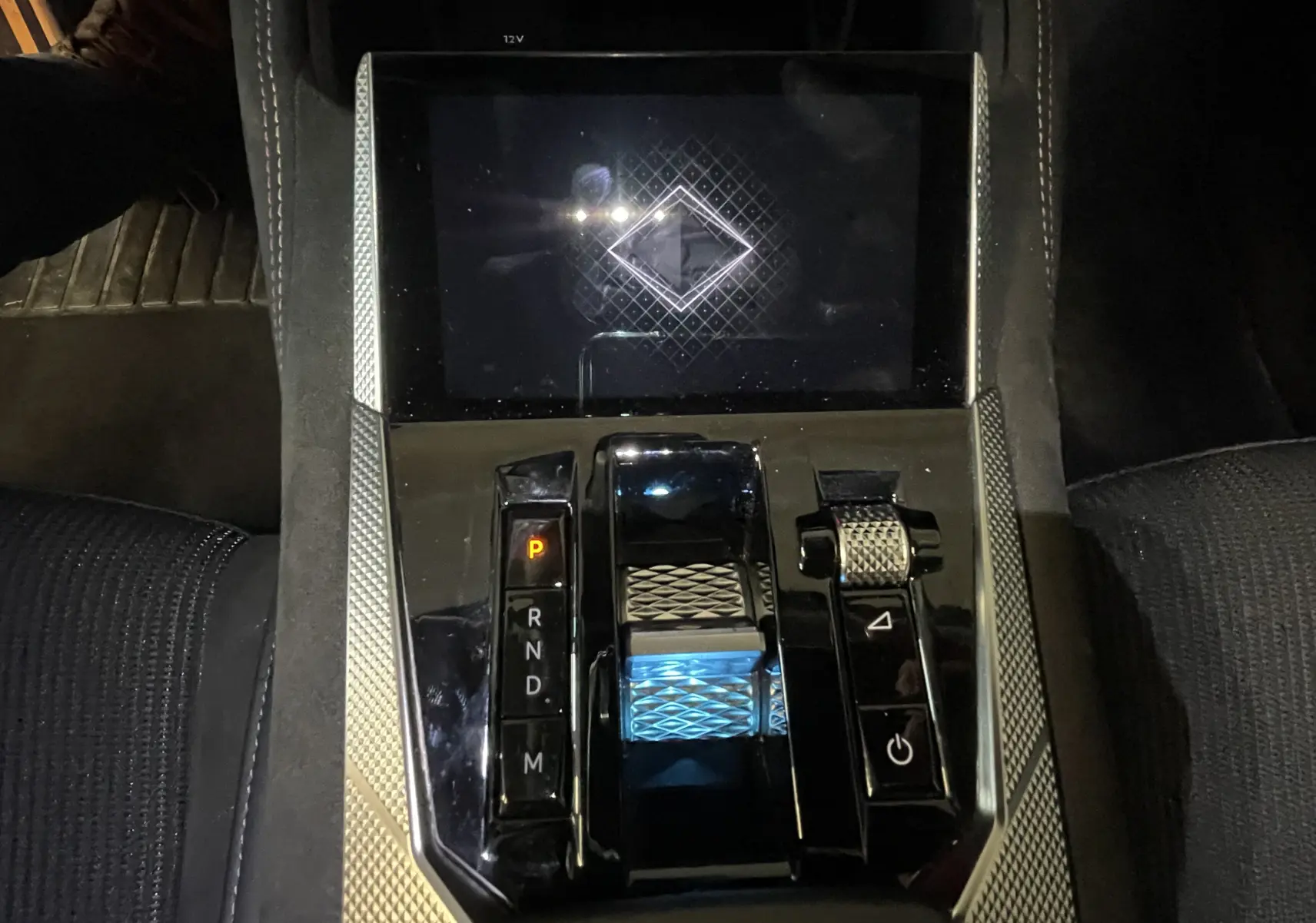Vue rapprochée de la console centrale du DS4 2024, avec levier de vitesse lumineux et sellerie tissu tressé basalte visible.