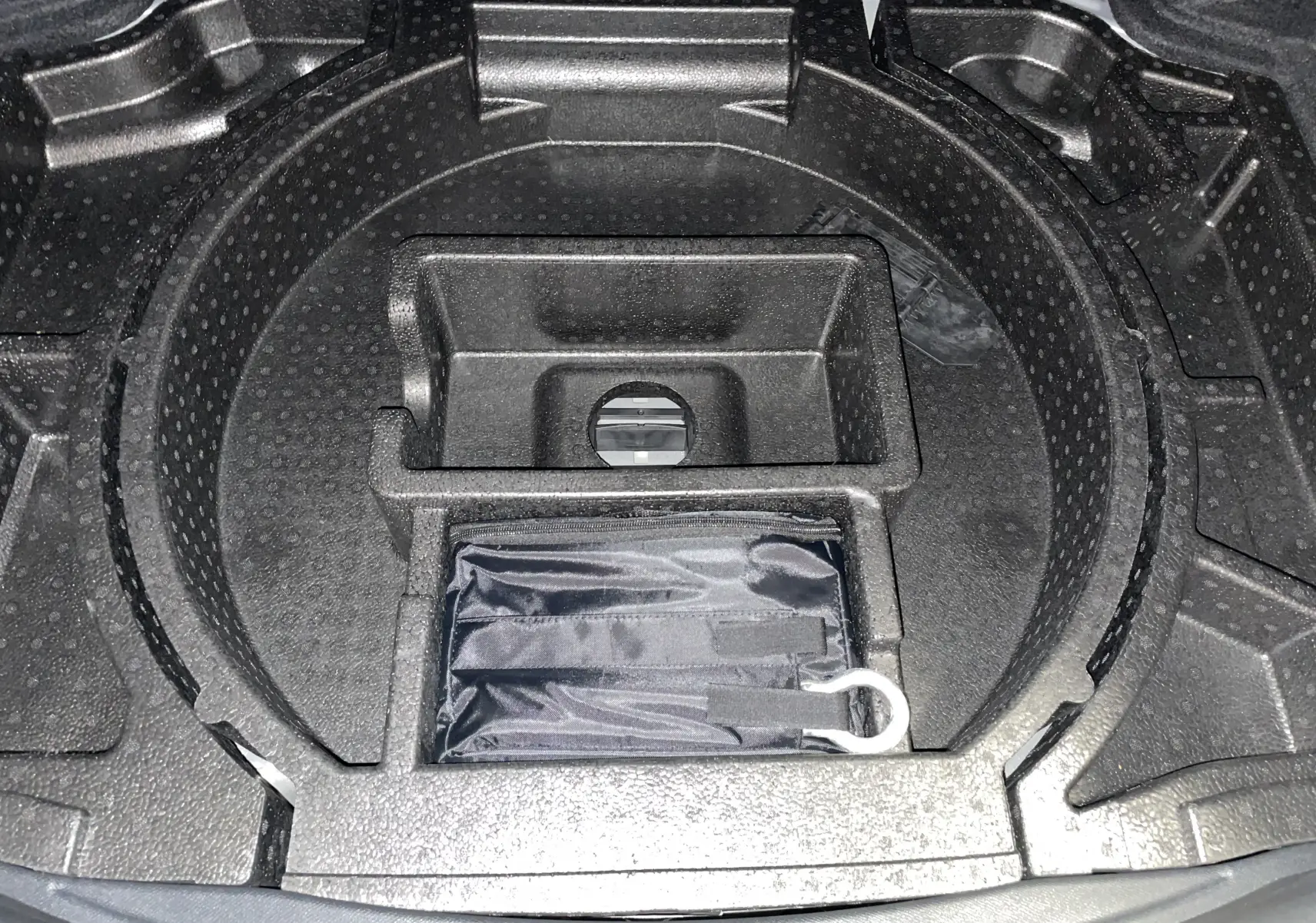 Compartiment de rangement sous le coffre du DS4 gris platinium, avec espace circulaire pour roue de secours et trousse noire.