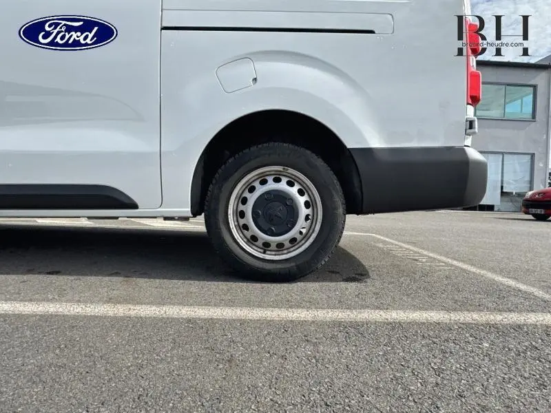 Vue latérale du côté gauche d'un fourgon blanc banquise avec roue arrière et porte coulissante visible.