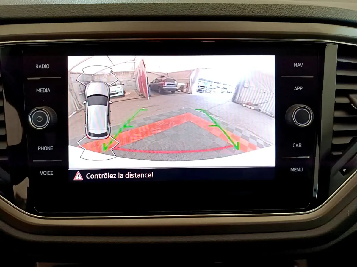 Écran tactile du Volkswagen T-Roc blanc montrant la caméra de recul avec guidage de trajectoire et avertissement de distance