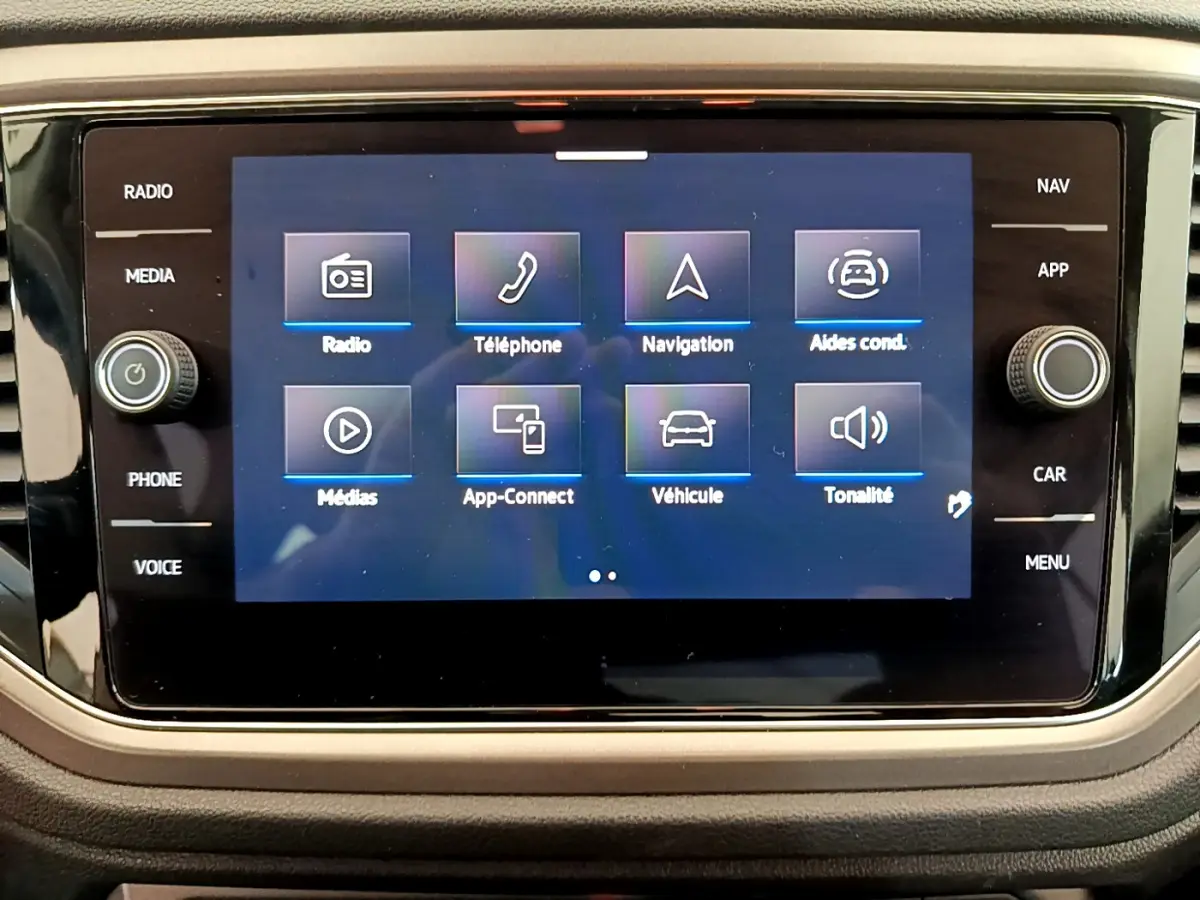 Écran tactile central du Volkswagen T-Roc blanc, affichant le menu principal avec options multimédia et navigation.
