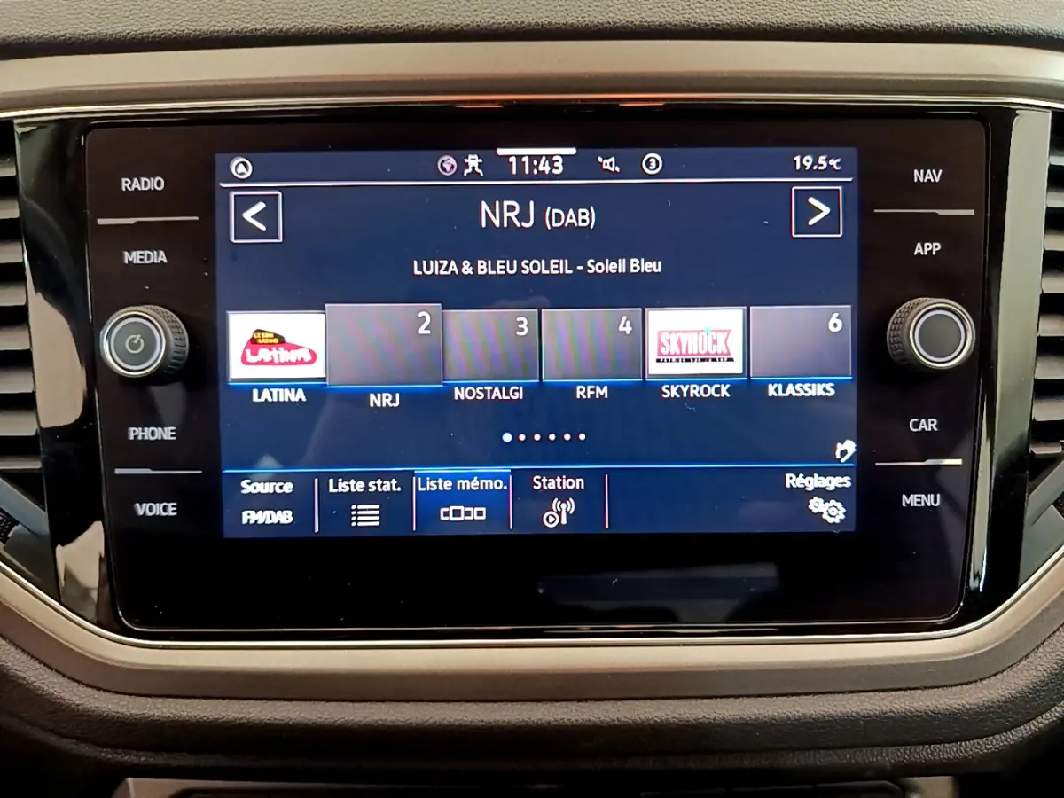 Écran tactile central du Volkswagen T-Roc blanc 2021 affichant les stations radio DAB, vue frontale rapprochée.