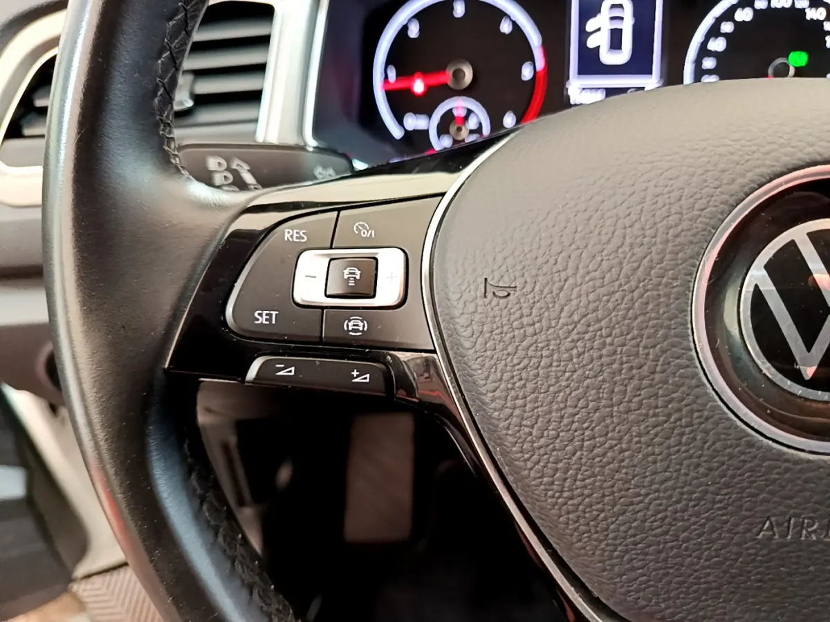 Gros plan sur le volant cuir multifonctions de la Volkswagen T-Roc 2021 avec commandes de régulateur de vitesse visibles.